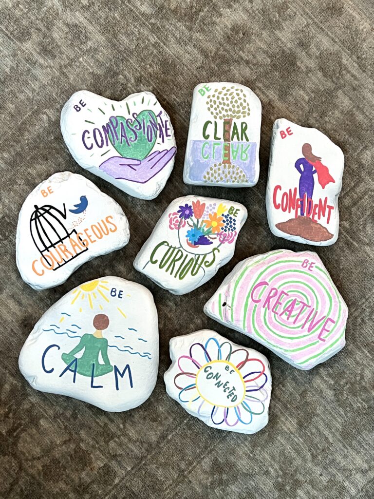 Painted stones lettered with the words calm, clear, curious, creative, courageous, confident and compassionate