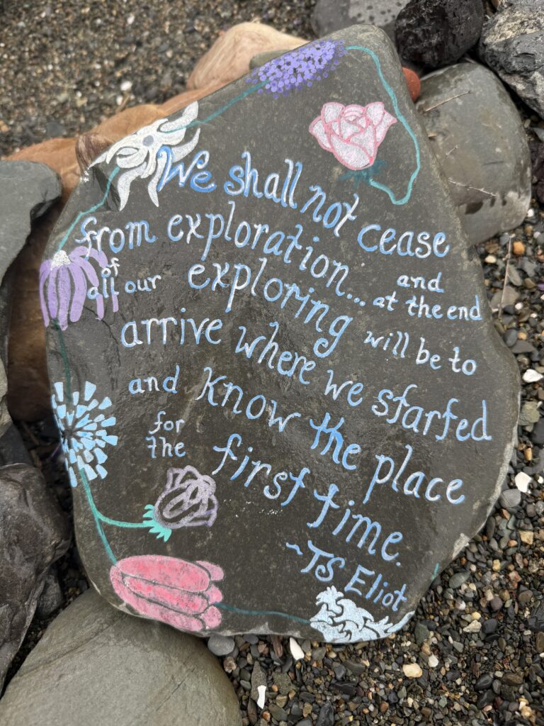 A painted beach stone lettered with the T.S. Eliot quote about not ceasing from exploration