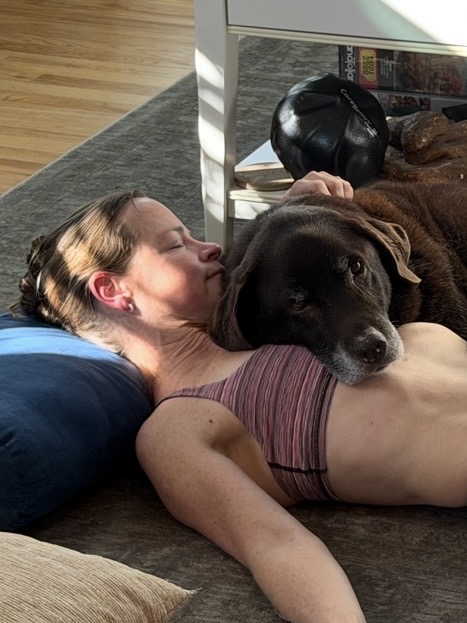Gretchen TenBrook lying on the floor nose to nose with a chocolate Labrador