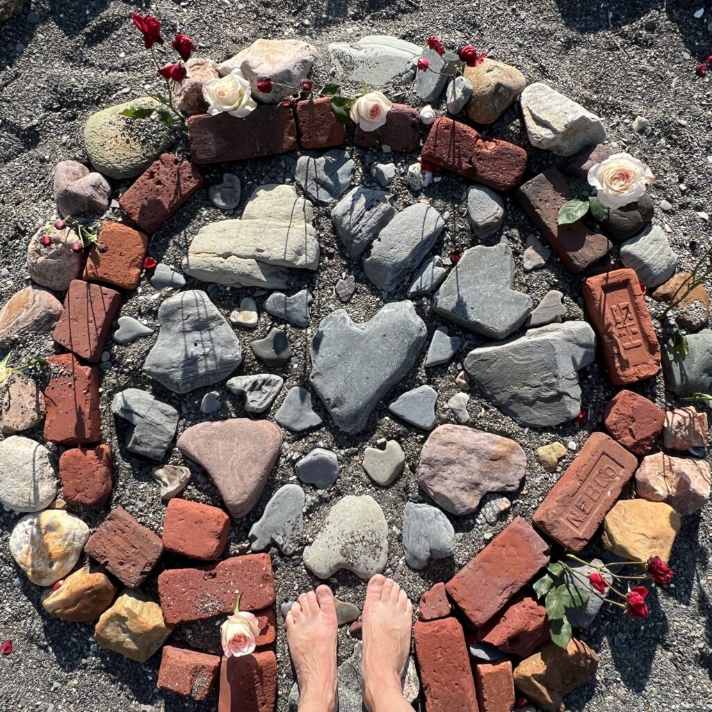 Overhead view of a stone and brick labyrinth with bare feet standing at its center